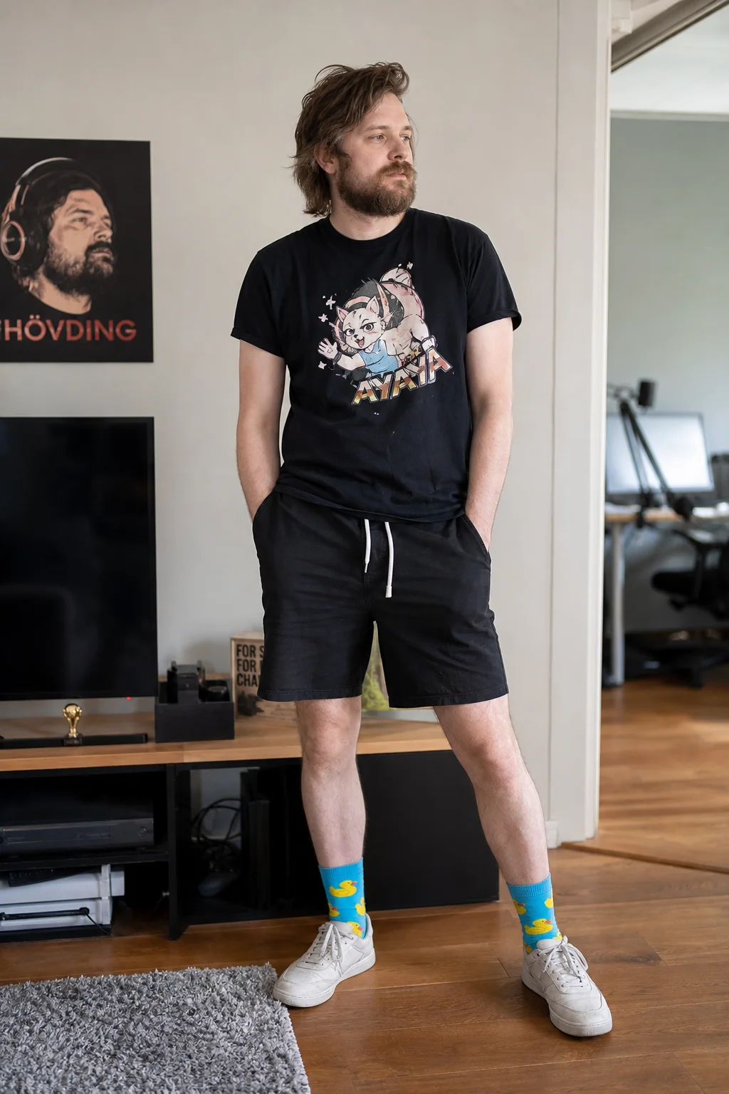 A casually standing person is photographed full-body indoors under soft natural light, wearing simple shoes and distinctive duck-patterned socks that are prominently visible.